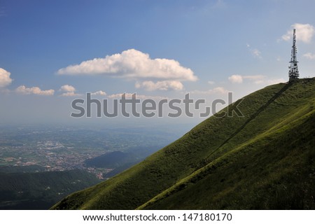 a television antenna watches over the valley from the top of a green hill, like a silent sentinel