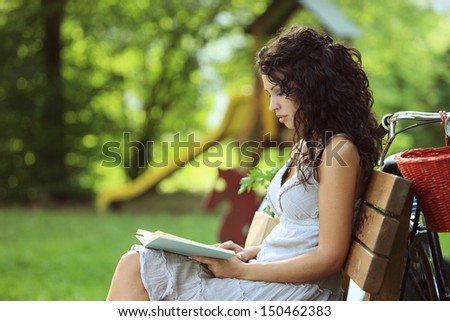 Young beautiful woman reading a book at a park
