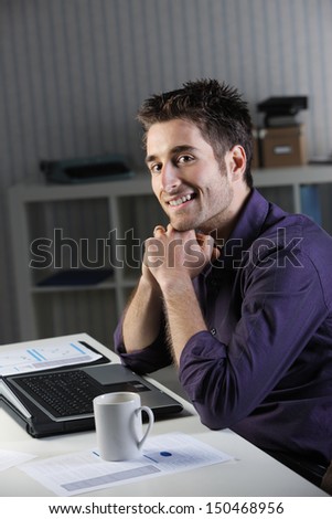 Cheerful young man working on laptop at home