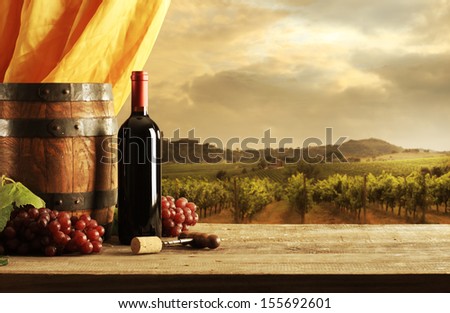 Red wine bottle, barrel and vineyard in sunset