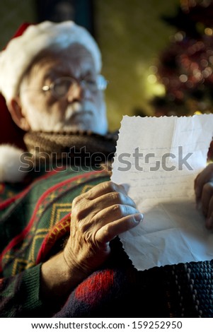 Portrait of Father Christmas sitting in armchair reading letters