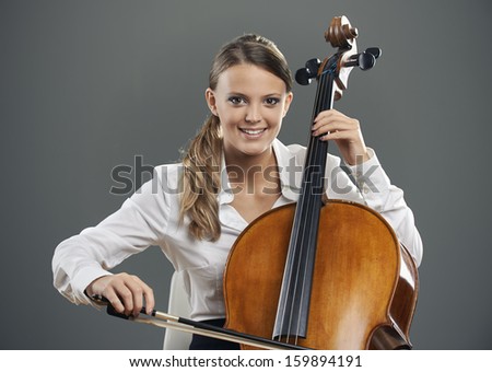 Smiling young woman cellist on grey background
