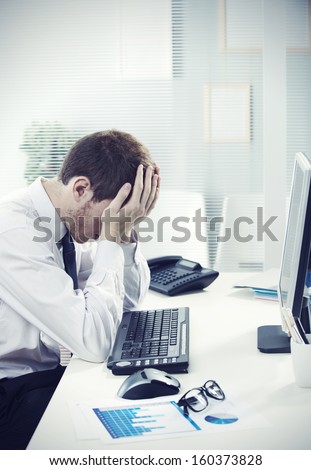A Worried Businessman Sitting At Office Desk