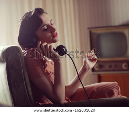 Vintage woman talking on retro phone at home