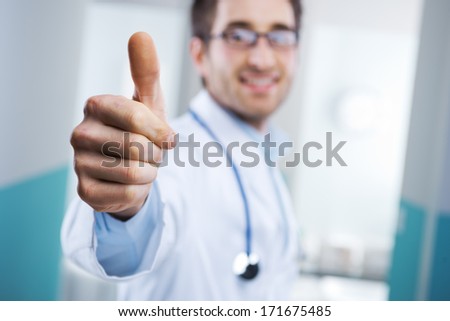 Young doctor expressing positivity and smiling with thumb up