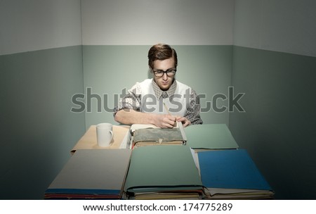 Nerd young man at desk in his small sad room.