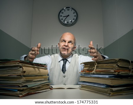 Angry office worker with piles of folders in a small room.