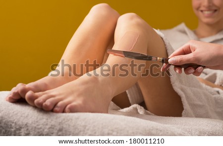 Woman receiving a waxing treatment on legs at spa.
