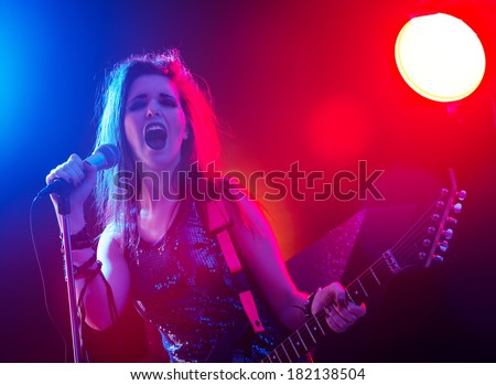 Young rock star singing with stage lights on background.