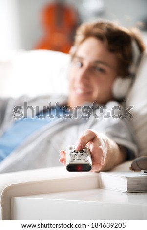 Guy listening to music with headphones holding stereo remote control.