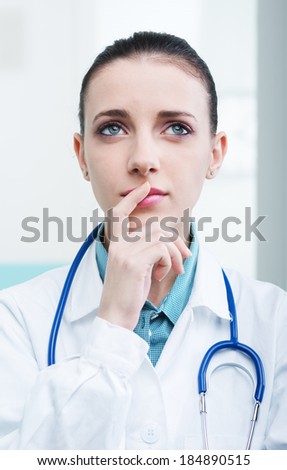 Portrait of a young female doctor thinking and looking up