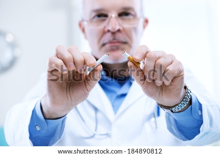 Senior doctor breaking a cigarette, stop smoking concept.