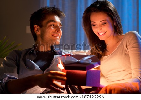 Young woman receiving a surprise gift box from her boyfriend at home.