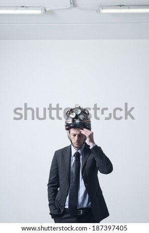 Tired pensive businessman touching his forehead wearing futuristic helmet with gauges.