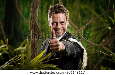 Attractive confident businessman with torn clothing in the jungle smiling with thumbs up.