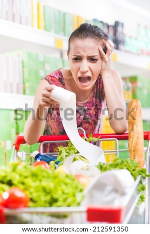 Young woman shouting and checking a long receipt at supermarket.