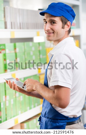 Young sales clerk holding a digital tablet and working at supermarket
