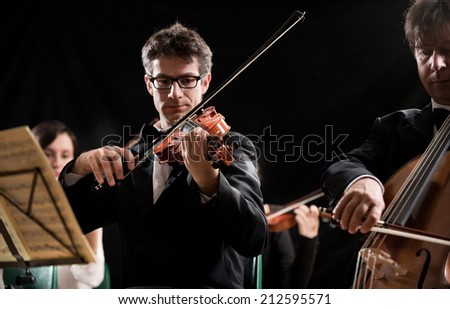 String orchestra performing on stage with violin and cello on foreground.