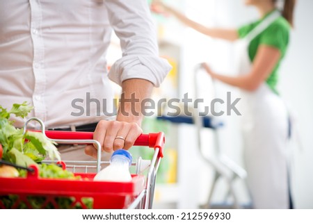 Supermarket customer\'s hand close-up with sales clerk on background.