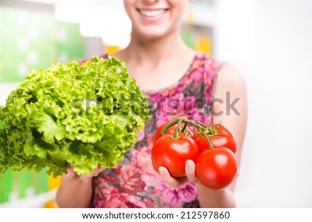 Woman holding fresh salad and tomatoes at supermarket.