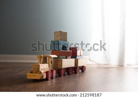 Vintage wooden toy train next to a window on hardwood floor.