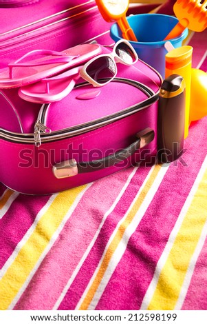 Striped colorful towel with pink bag, sunglasses and sun creams.