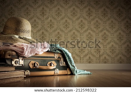 Holiday packing with vintage suitcase and polka dot clothing on hardwood floor.
