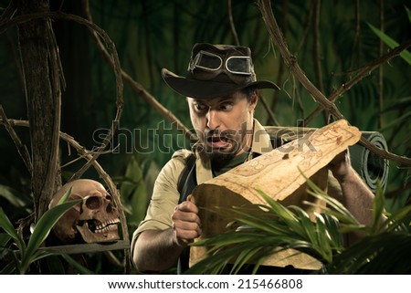 Explorer with old map in the jungle discovering a human skull.