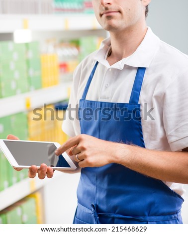 Young sales clerk holding a digital tablet and working at supermarket.