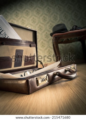 Vintage businessman open briefcase on the floor with financial newspaper and hat.