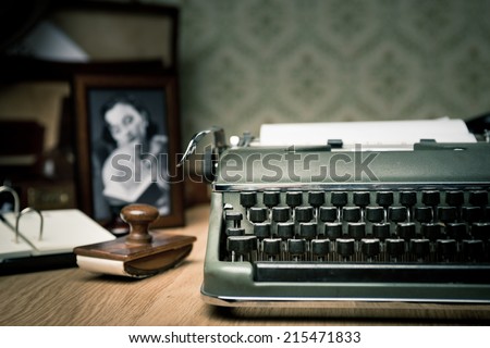 Vintage typewriter on a wooden desk with old frame and picture on background.