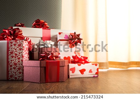 Plenty of elegant christmas gifts on hardwood floor in white and red tones.