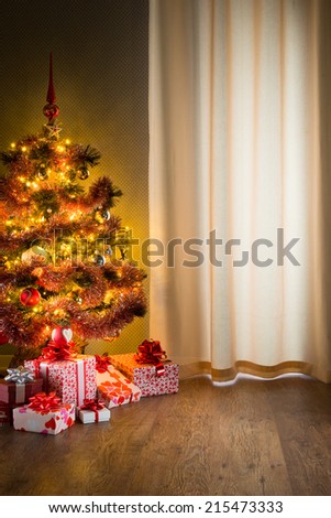 Colorful christmas tree with red and white gift boxes on elegant hardwood floor.