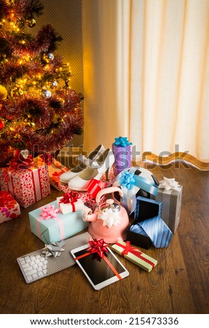 Christmas gifts for all family under decorated tree with lights and colorful baubles.