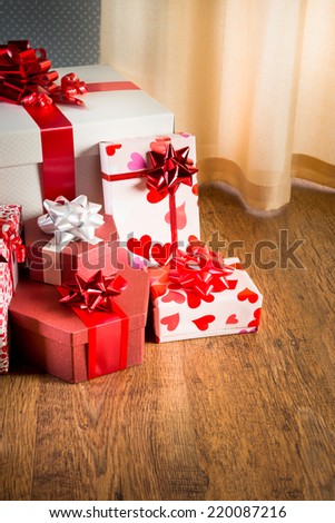 Plenty of elegant christmas gifts on hardwood floor in white and red tones.