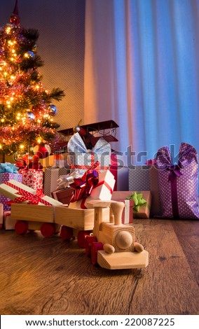 Wooden toy train with special gift and christmas tree on background.