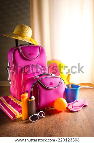 Summer holidays background with pink bag, sun cream, flip flops and beach toys.