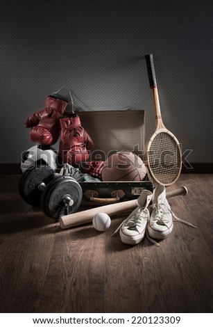 Teenager sport equipment in a vintage suitcase including sports footwear, boxing gloves, weights and baseball bat.