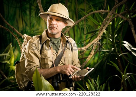 Colonial style adventurer with digital tablet exploring jungle wilderness Colonial style adventurer with digital tablet exploring jungle wilderness