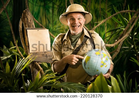 Cheerful explorer in the jungle pointing to a globe next to a wooden sign.