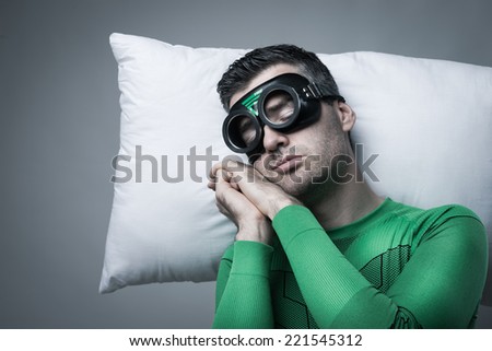 Superhero sleeping on a pillow floating in the air with hands clasped.