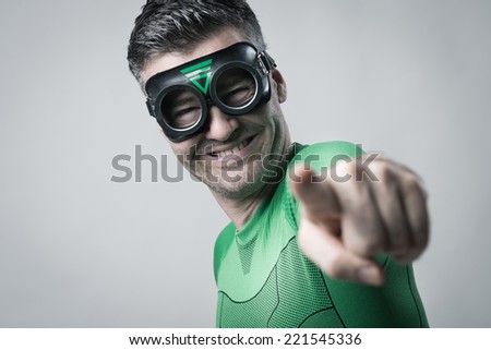 Cheerful green superhero smiling and pointing at camera.
