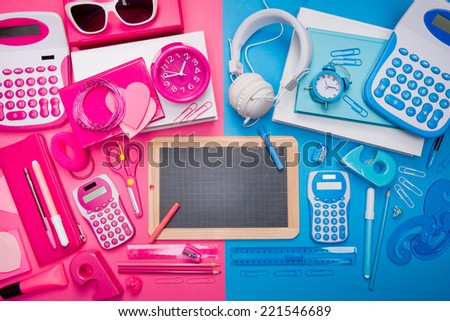 Boy and girl desktop with pink and blue stationery and blackboard at center.
