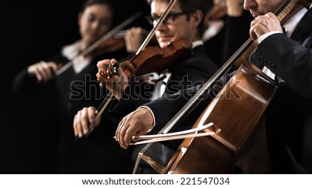 String orchestra performing on stage with cello on foreground.