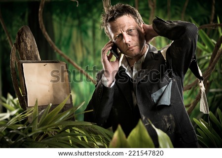Lost businessman in the jungle with mobile phone and empty sign.