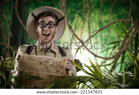Young smiling explorer in the jungle with thick glasses holding a map.