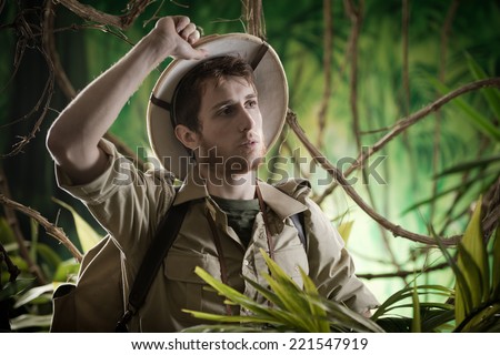 Tired young adventurer exploring the forest with hand on pith hat.