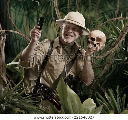Smiling explorer taking a self portait with a skull in the jungle.
