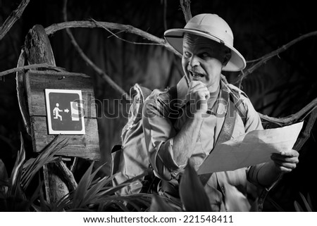 Surprised explorer holding a map and finding an exit sign in the jungle.