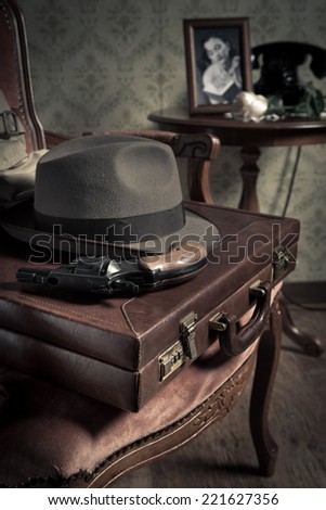 Detective equipment with briefcase, hat and gun, vintage interior on background.